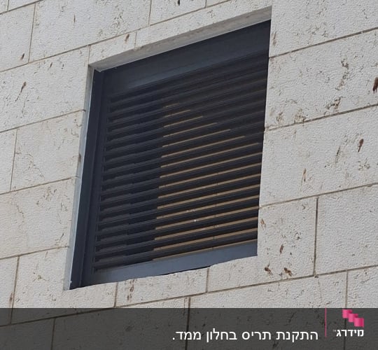 מסתור אלומיניום כהה עם שלבי רפפות בקיר חיצוני מחופה אבן